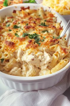 a casserole dish filled with chicken and noodles, garnished with parsley