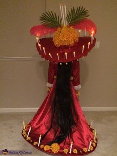 a woman with long black hair wearing a red dress and lighted candles on her head