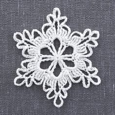 a crocheted snowflake is shown on a gray surface with white thread