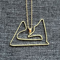 a gold necklace with a dog's head in the shape of a mountain on it