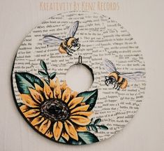 a sunflower and bee painted on a white disc with words written in the background