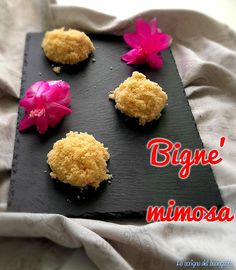 three small desserts on a black plate with pink flowers and the words'bigne nimosa '