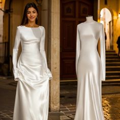 a woman standing next to a mannequin in front of a building wearing a white dress