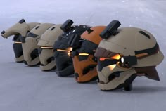 several helmets are lined up in a row on the snow, with lights glowing from them