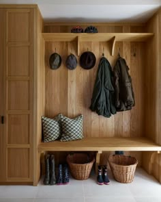 a wooden bench with baskets and hats hanging on the wall next to two coat racks