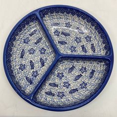 a blue and white plate with birds on it sitting on a counter top next to a wall