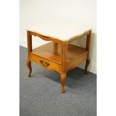 a small wooden table with a marble top on carpeted floor next to a wall