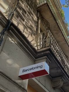 a street sign hanging from the side of a building next to a balcony and balconies