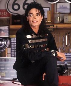 michael jackson sitting on top of a counter in a room with clocks and other items