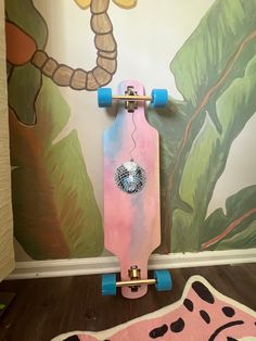 a pink skateboard sitting on top of a wooden floor next to a wall mural