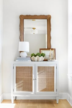 a white sideboard with wicker doors and a mirror on top in a room