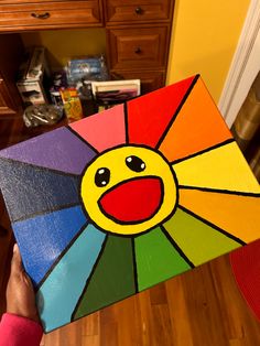 a person holding up a colorful piece of art that looks like a smiley face on it