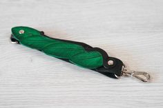 a green and black feathered umbrella keychain on a white surface