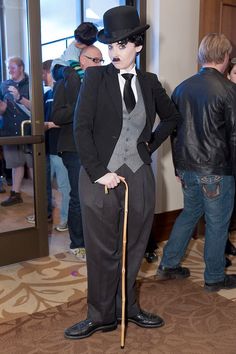 a man in a suit and top hat with a cane standing next to other people