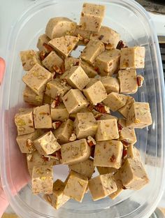 a person holding a plastic container filled with tofu