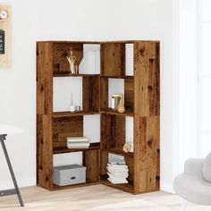 an open bookcase in the corner of a room with a white chair and table