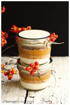 three jars filled with food sitting on top of a white wooden table next to orange flowers