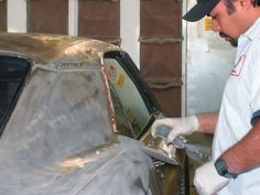 a man in white shirt waxing a car