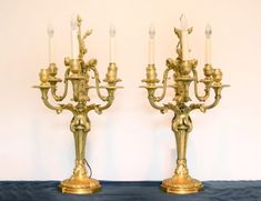 two brass candelabra with candles on top