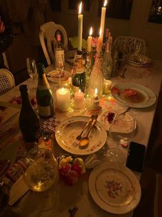 a dinner table is set with candles, plates and wine bottles for the guests to enjoy