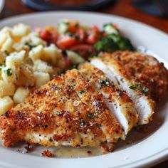 a white plate topped with chicken, potatoes and broccoli covered in seasoning