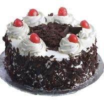 a black forest cake with white frosting and cherries on top, sitting on a plate