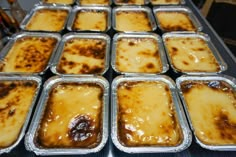 many trays of food sitting on top of a metal table covered in brown sauce