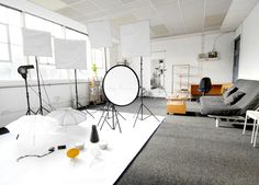 a photo studio with chairs, lights and lighting equipment on the floor in front of large windows