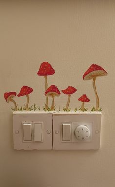 some red mushrooms are sitting on top of a light switch cover in the bathroom wall