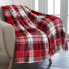 a red and green plaid blanket sitting on top of a couch next to a window