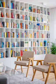 two chairs sitting in front of a book shelf filled with books