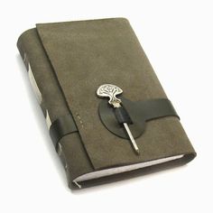 a small notebook with a pen sticking out of it's front cover, sitting on a white surface