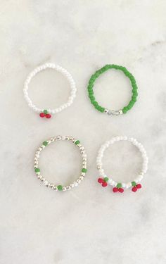 three different bracelets with beads on them sitting on a marble surface, one in green and the other in white