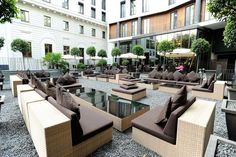 an outdoor seating area with couches, tables and umbrellas on the ground in front of a building