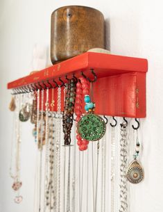 a red shelf with many necklaces hanging from it