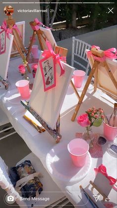 a table topped with pink cups and easels covered in cards, pictures and other items