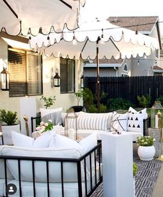 an outdoor living area with white couches and tables