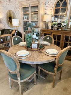 a dining room table set for four with plates and place settings on the centerpiece