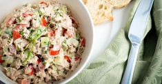 a white bowl filled with tuna salad next to bread