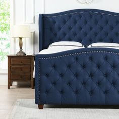 a blue upholstered bed in a bedroom with a clock on the wall behind it