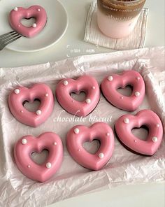 pink heart shaped donuts with white pearls in the shape of hearts on wax paper