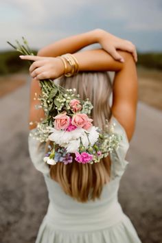 a woman with flowers in her hair is walking down the road wearing a flower crown