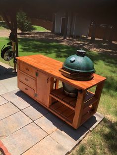 a big green egg sitting on top of a wooden table next to a bbq