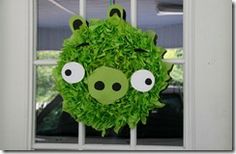 a wreath made to look like a green pig with googly eyes on the front door