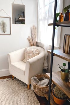 cozy white chair with natural woven rug, pampas grass, gray walls, sheer white curtain, bookshelf with plants and cactus