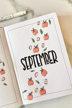 an open notebook with the word september written in black ink on it next to a pencil