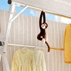 a monkey hanging from a clothes rail next to a yellow shirt