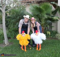 a man and woman are posing with two chickens