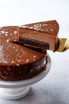 a piece of chocolate cake on a white plate with a gold serving knife in it