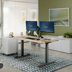 two computer monitors sitting on top of a wooden desk next to each other in an office